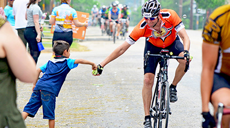 a boy giving a cylist a high five during the MS Society bike ride