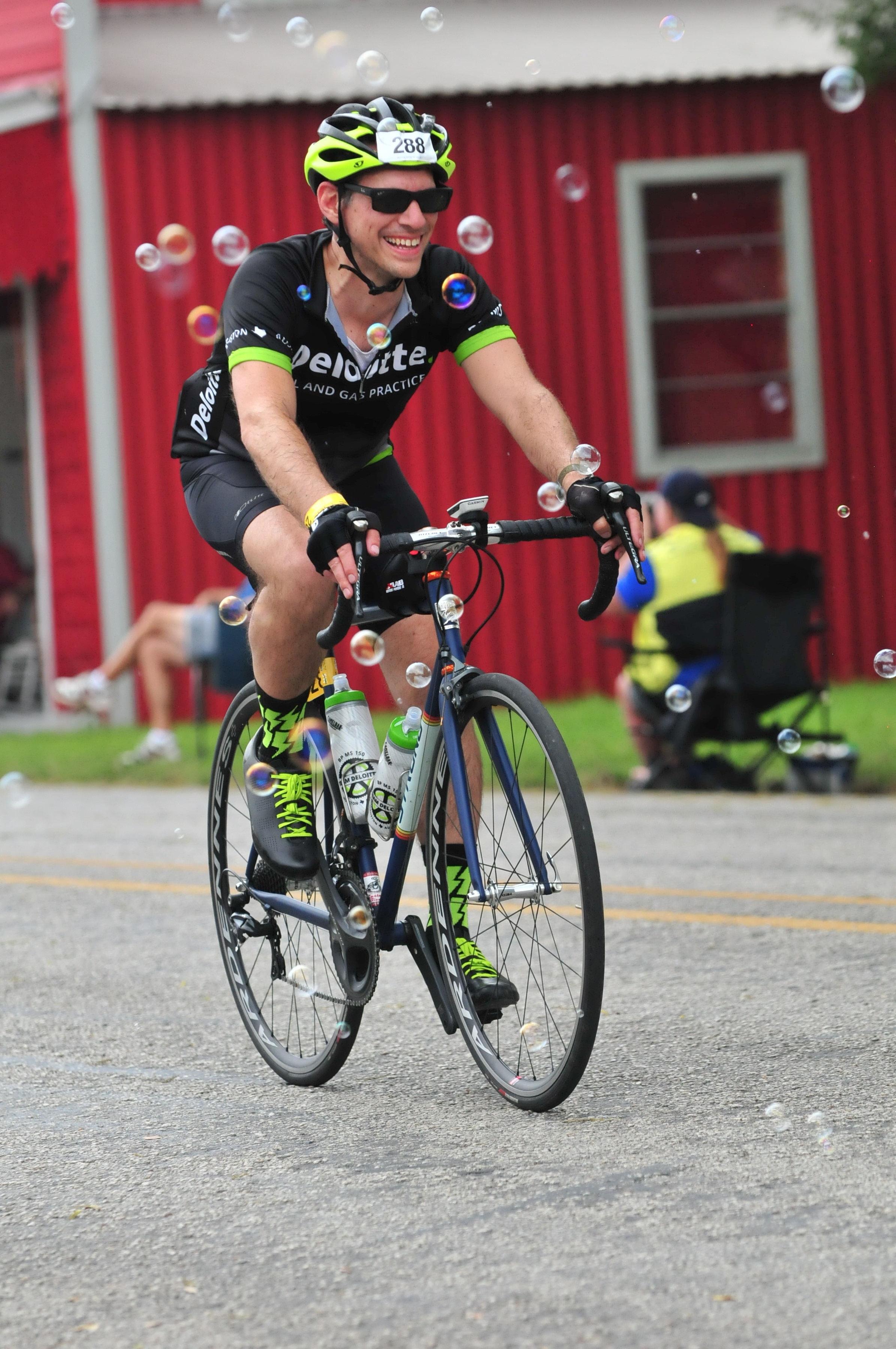 Deloitte cyclist riding his bike as fans blow bubbles